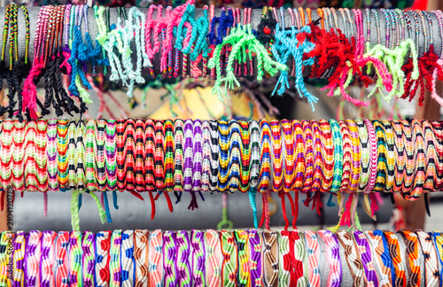 Assortment of colorful handmade woven friendship bracelets displayed in rows on a market stall shelf