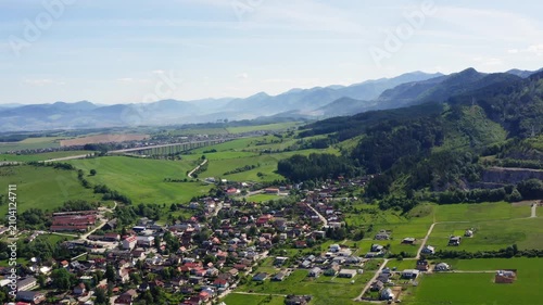 4K aerial view of Turie village in Zilina region, Slovakia. Beautiful panoramic shot of countryside houses, green fields, and the D1 highway bridge with Mala Fatra mountains background