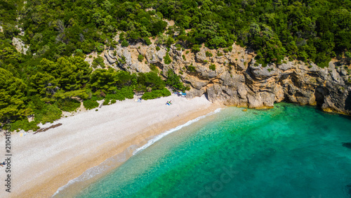 Foto Pristine pebble beach and turquoise waters meet lush cliffs on the stunning Adriatic coast