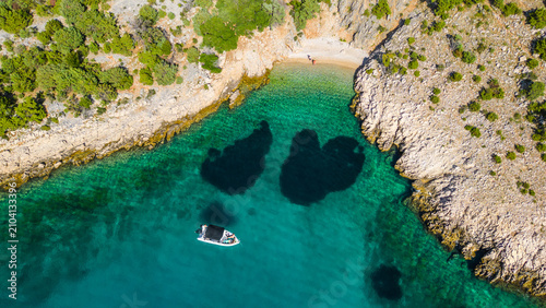 Obraz na płótnie Aerial view of a secluded Adriatic cove with crystal-clear turquoise waters, a small beach, and a boat enjoying the summer sun