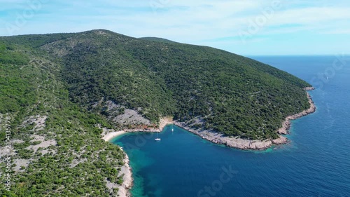 Discover the tranquil beauty of a secluded Croatian cove. Crystal-clear Adriatic waters, lush green hills, and a lone sailboat invite pure relaxation. Perfect summer escape. Beach Grabrovica