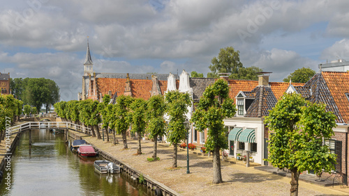 Foto Historic canal scene with boats and church spire in Sloten, Friesland, Netherlan