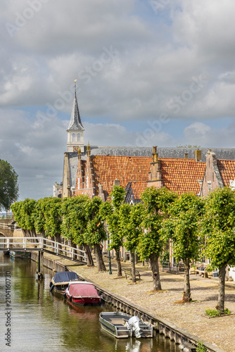 Schilderij op canvas Historic canal scene with boats and church spire in Sloten, Friesland, Netherlan