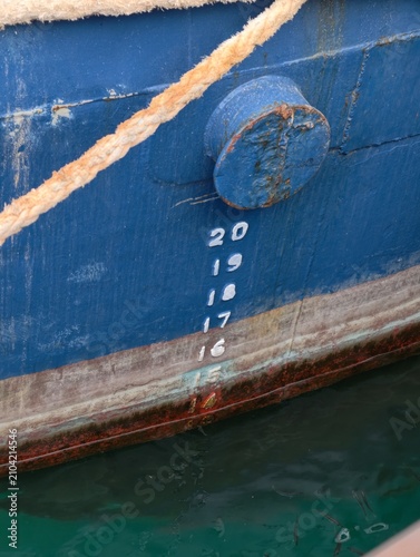 Foto Close-up of a blue fishing boat hull with draft marks at the waterline
