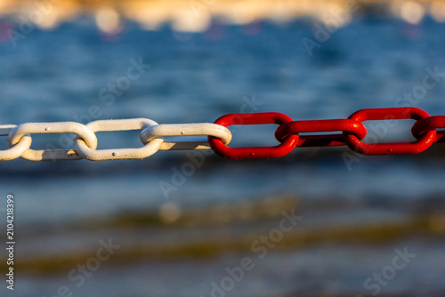 Картината върху платно Red and White Chain Link by the Sea Symbolizing Connection, Contrast, and Nautic