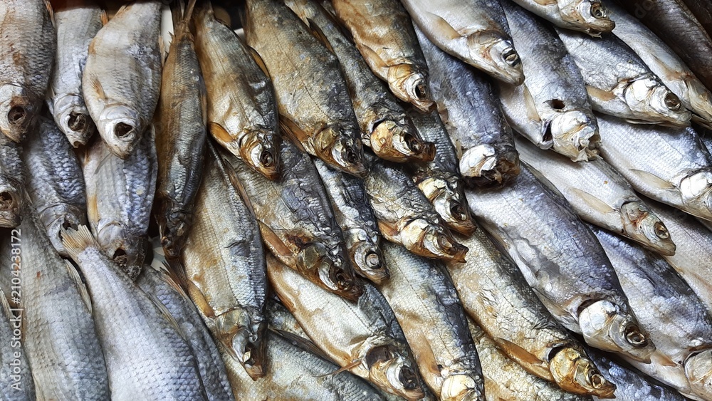 Obraz premium A selection of dried and smoked fish—a traditional beer snack. A close-up of freshly prepared fish delicacies, including Caspian roach, sabrefish, whitefish, and other varieties. Natural scale texture