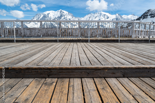 Canvastavla une terrasse de bois d'une station face à une chaine montagneuse enneigée