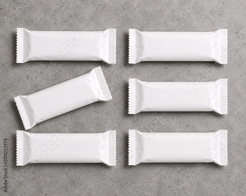 Top view of six blank white snack bar packaging mockups on grey concrete