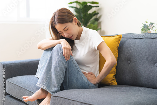 Sick asian young woman in pain, hand holding belly, stomach pain from food poisoning, girl hurt abdomen ache and digestive problem, gastritis or diarrhea. Health care inflammation, abdominal problem