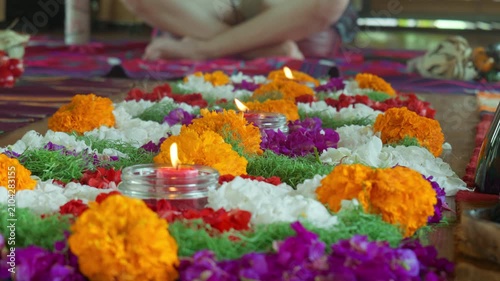 The Altar flowers and candles sits on a wooden floor.