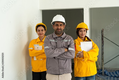 Obraz na plátně Asian construction worker and safety team at construction site wearing helmet an