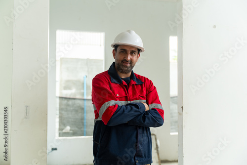 Quadro su tela Asian construction worker wearing safety helmet and uniform stands confidently a