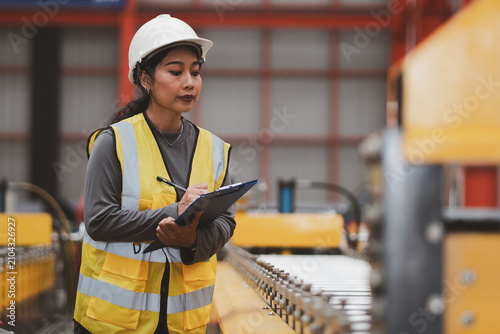 Industrial equipment inspection. Female engineer checks machine components and records maintenance data inside a modern factory. Inspection, engineer, machinery, maintenance, industry