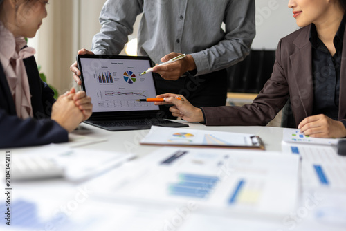 Business team analyzing financial data on laptop screen.