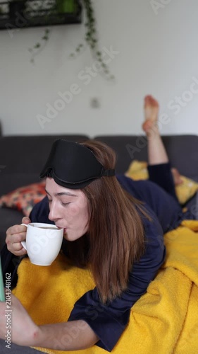 Vertical screen Morning video call and fresh coffee help a young woman ease into the day as she chats with a friend enjoying a cozy start before daily responsibilities