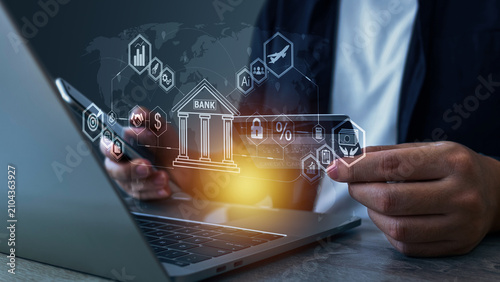 A person uses a laptop with digital banking icons floating around, representing online banking, financial technology, AI, cybersecurity, investment, and digital transformation in the banking industry.