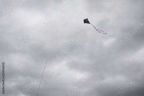 Broken kite string, kite drifting away in gray overcast sky, minimalist composition.