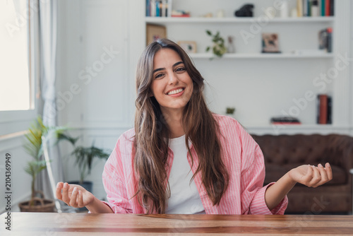 Cuadro en lienzo Young woman sitting at a table in a home office smiling confidently at the camer
