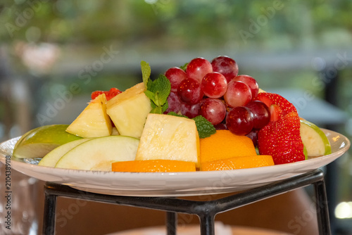 Fresh mixed fruit platter with grapes pineapple apples strawberries oranges and mint served for healthy restaurant breakfast buffet