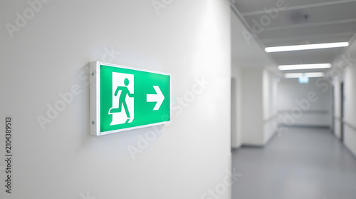 Green Illuminated Emergency Exit Sign in Modern Hallway