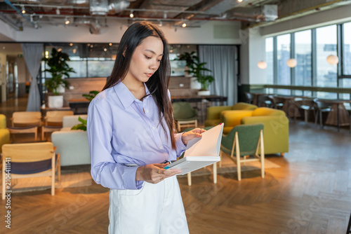 Woman Reads a Notebook in a Modern Indoor Space With Plants