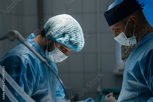 Obraz na plátně Multidisciplinary surgical team performing operative treatment in a modern hospi