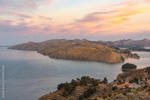 Sunset over Isla del Sol on Lake Titicaca, Bolivia, with golden light illuminating the island's rugged hills and the tranquil waters of the world's highest navigable lake