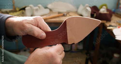 Artisan occupation. Footwear industry. Professional craftsman hands working with leather material shoe sole at workplace.