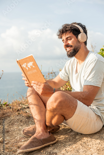 Man enjoying digital detox reading travel journal on cliff