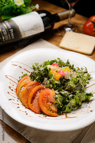 Quadro su tela Fresh tomato salad with greens on white plate