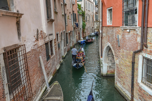 Italy, Venice, Octoberber 01, 2025, A gondolier in a black and white striped shirt is transporting tourists in Venice