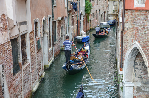 Italy, Venice, Octoberber 01, 2025, A gondolier in a black and white striped shirt is transporting tourists in Venice