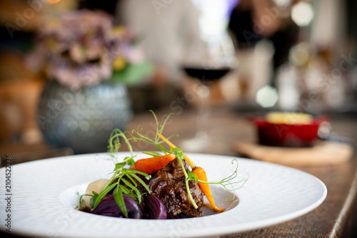 Bild auf Leinwand Delightful Gourmet Dish Beautifully Presented on a Wooden Table in a Cozy Restau
