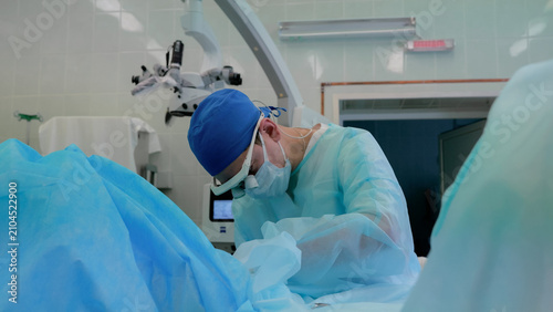 Foto Focused surgeon in blue cap and sterile gown working during delicate operation i