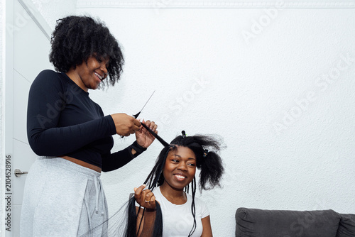 Black women braiding hair extensions at home