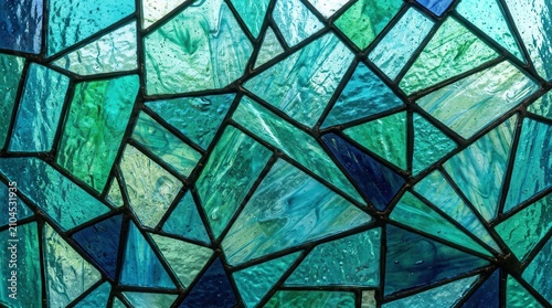 A detailed view of a textured stained glass window with an abstract blue and green geometric design.
