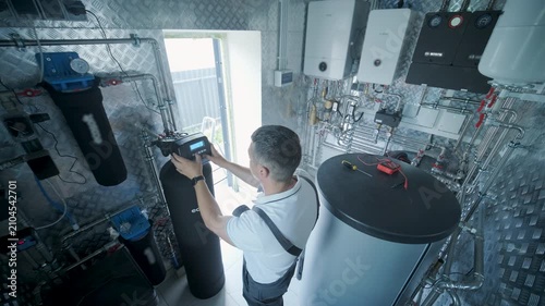 Technician maintaining whole house water purification and softening system in a mechanical room.