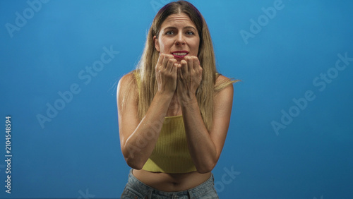 Foto Woman cupping hands near mouth and pleading with worried expression wearing yellow crop top and jeans in studio; anxiety plea