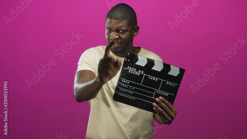 Foto Young black man holding clapperboard and pointing finger at camera in studio; confidence assertiveness