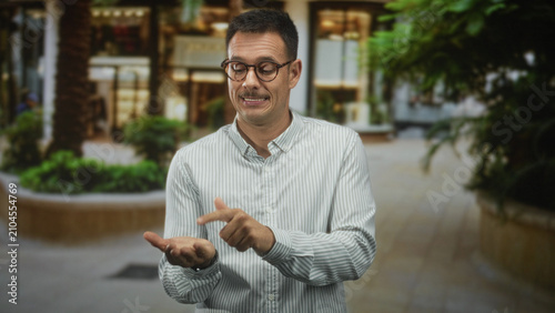 Canvastavla Man with mustache and glasses in striped shirt holds open palms and gently shrugs in building; uncertainty