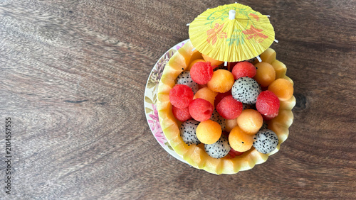 Fresh tropical fruit bowl in carved melon with watermelon, cantaloupe and dragon fruit on wooden table top view