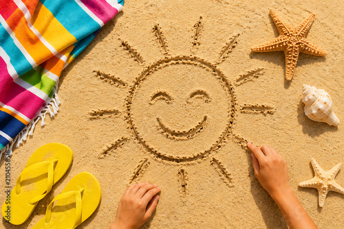 Summer beach smiling sun happy smiley face drawing drawn in sand with accessories holiday vacation photo