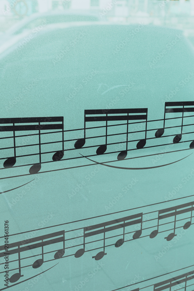 Fototapeta premium Musical Notes on Glass Window with Urban Street Reflection