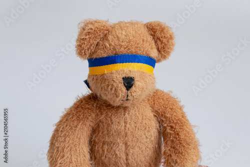 Fotografía A teddy bear blindfolded with a ribbon in the colors of the Ukrainian flag, depi