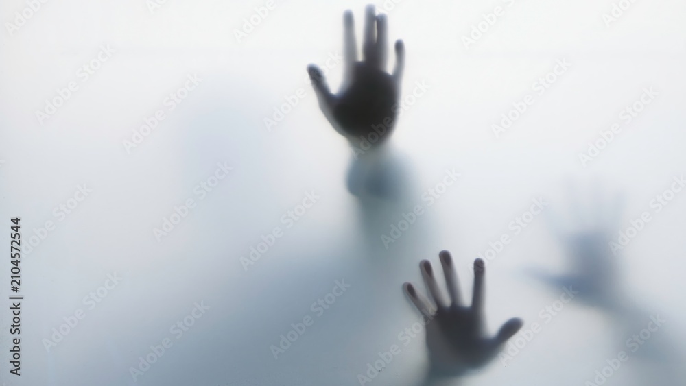 Obraz premium Dark hand silhouettes pressed against frosted glass