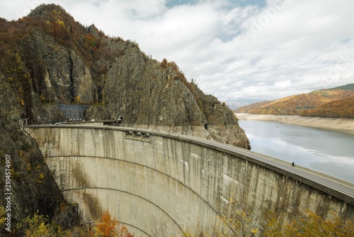 Fotografía Vast cracks mar the empty lake bed of Vidraru dam, framed by towering cliffs ado