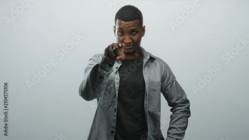 Canvastavla Man pointing finger to camera with hand near neck, wearing black shirt in studio portrait; confidence direct challenge