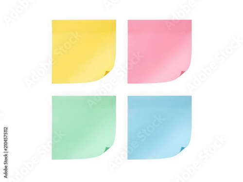 Four colorful sticky notes in yellow pink green and blue square paper sheets for office reminders