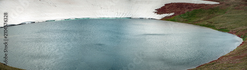 High Altitude Crater Lake with Melting Snow Shelf and Turquoise Water Edge