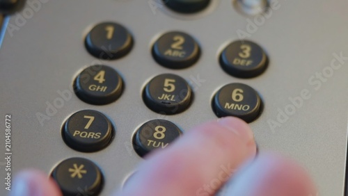 Foto Close-up fingertip pressing numeric keypad on office desk telephone under warm d